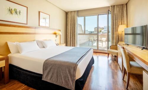 マドリードにあるイルニオン アルカラ ノルテのベッド、デスク、テレビが備わるホテルルームです。