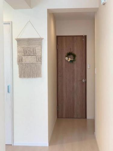 a hallway with a wooden door with a wreath on it at Condominium Luana 築浅2LDK 宮城海岸徒歩2分 American Village 車で10分 in Chatan
