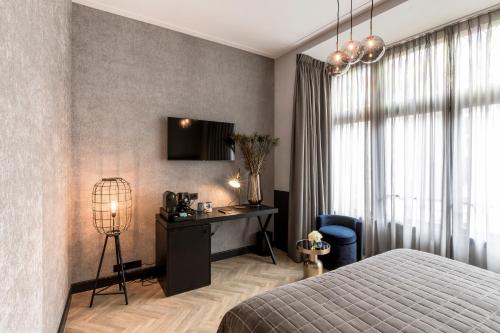 a bedroom with a bed and a desk and a television at Cavallaro Hotel in Haarlem