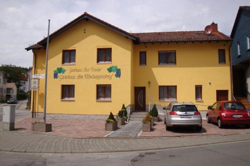 a yellow building with cars parked in front of it at Gaestehaeuser Am Nibelungensteig in Lautertal