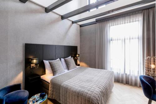 a bedroom with a bed and a window and chairs at Cavallaro Hotel in Haarlem