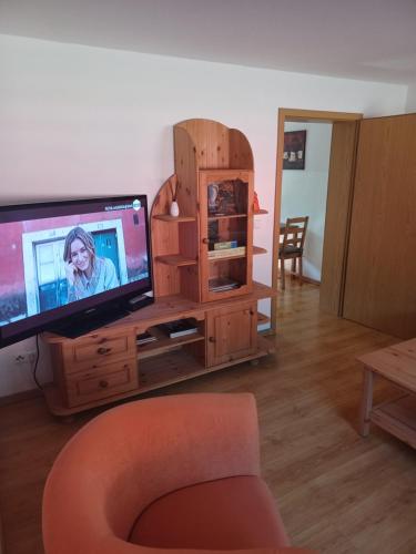 a living room with a television on a wooden entertainment center at FeWo s Runde Wiese RW in Greifswald