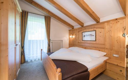 1 dormitorio con 1 cama con pared de madera en Appartementhaus Residence Hirzer en Tirolo