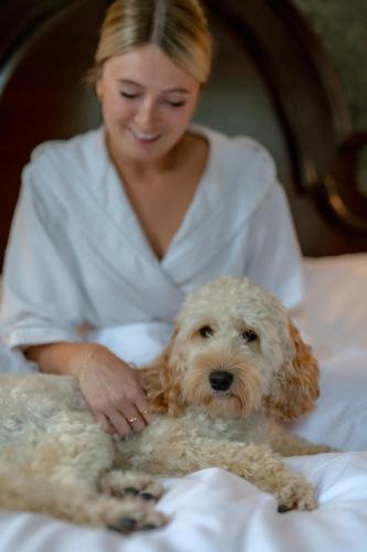 a woman in bed with a dog on a bed at Melville Castle Hotel in Edinburgh