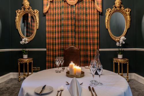 a dining room with a table with a candle and mirrors at Melville Castle Hotel in Edinburgh