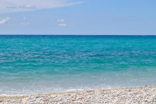 a beach with blue water and a rocky shore at Casa a Cocca in Briatico