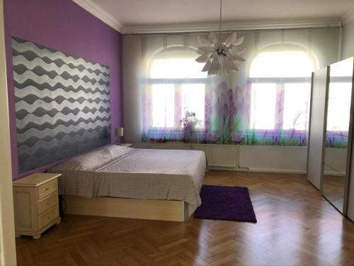 ein Schlafzimmer mit einem Bett sowie violetten Wänden und Fenstern in der Unterkunft Ferienwohnung an der grünen Clara in Erfurt
