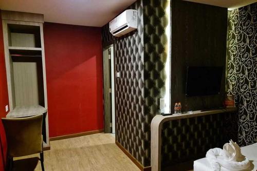 une chambre d'hôtel avec un mur rouge et noir dans l'établissement RedDoorz Plus near Nagoya Hill Batam 6, à Bumiayu