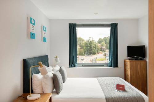 een slaapkamer met een groot bed en een raam bij HQ Aparthotel Farnborough in Farnborough