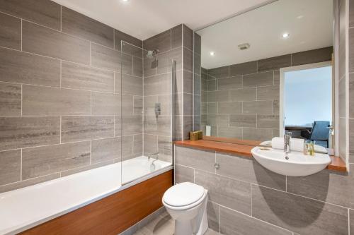 a bathroom with a toilet and a sink and a bath tub at HQ Aparthotel Farnborough in Farnborough