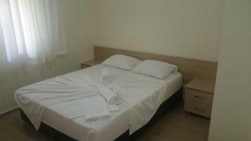 uma cama branca com duas almofadas e uma mesa de cabeceira em Tunali Apart Hotel em Antalya