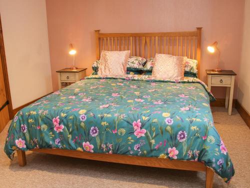 a bedroom with a large bed with a floral bedspread at Meadow Barn in Craven Arms