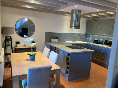 a kitchen with blue cabinets and a table with chairs at Ryelands Cottage in Totnes