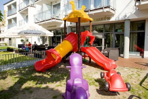 un parque infantil con equipo de juegos colorido frente a un edificio en Hotel Jastarnia en Jastarnia