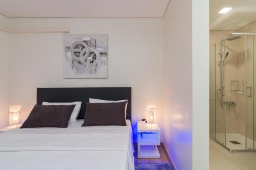 a bedroom with a white bed and a glass shower at Casas Madalena in Seia