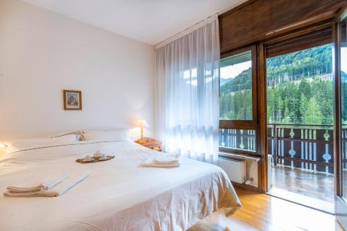 a bedroom with a large bed and a large window at Il Ruscello Apartment with Terrace and View of the Alps in Tarvisio