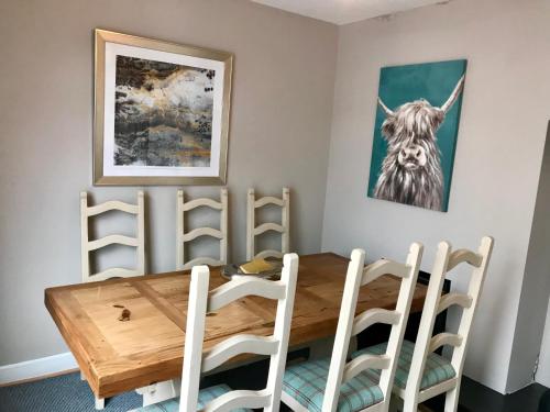 a dining room with a wooden table and white chairs at Rose Cottage: Delightful 4 bedroom detached home in Portrush