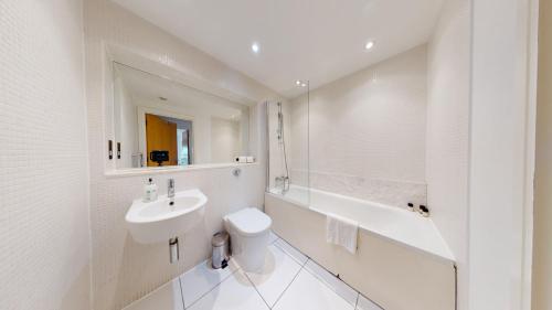 a bathroom with a sink and a toilet and a tub at Spacious Serviced Apartments Canary Wharf in London