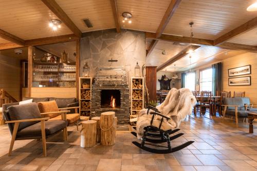 a living room with a stone fireplace and tables and chairs at Lapland Hotels Ounasvaara Chalets in Rovaniemi