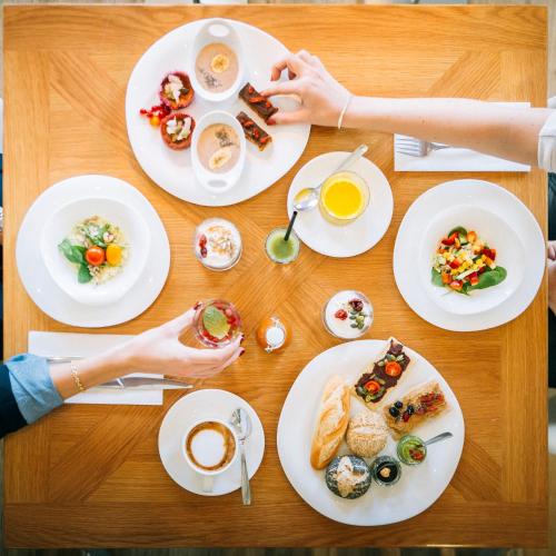 a table with plates of food and a person holding a cup of coffee at Petit Palace Savoy Alfonso XII in Madrid
