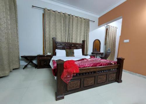 Un dormitorio con una gran cama de madera con sábanas rojas. en Hotel Orash Lodge en Nāluchhi