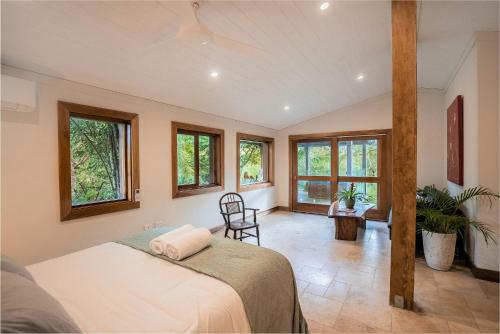 een slaapkamer met een bed in een kamer met ramen bij Palm Grove Rainforest Retreat in Palm Grove