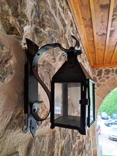 a black lantern hanging on a stone wall at Guest Mansion, Гостински Палат in Rostuša