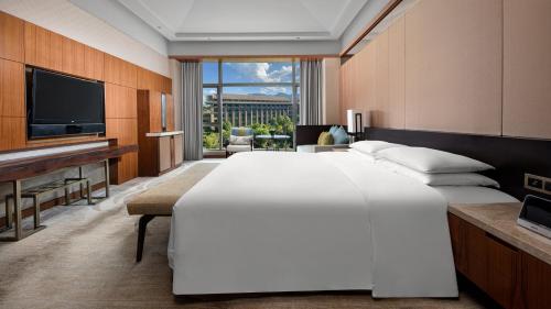 a large bedroom with a large bed and a television at InterContinental Kunming by IHG in Kunming