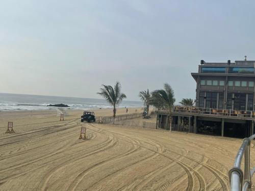 ciężarówka jeżdżąca po piaszczystej plaży z palmami i budynku w obiekcie Room near the Beach and Pier Village w mieście Long Branch