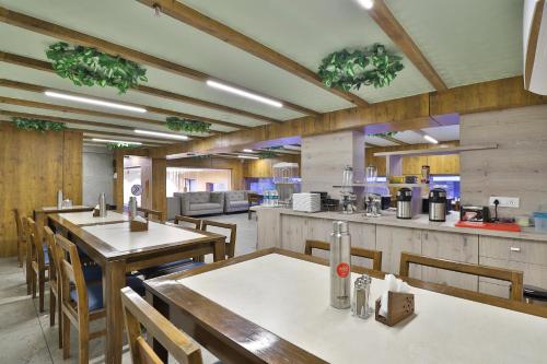 a restaurant with tables and chairs and a kitchen at 7 Orbit Hotel, Surat in Surat