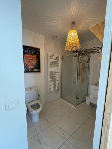 a bathroom with a toilet and a shower and a chandelier at Appartement avec jardin entre lac et océan Hossegor in Soorts-Hossegor