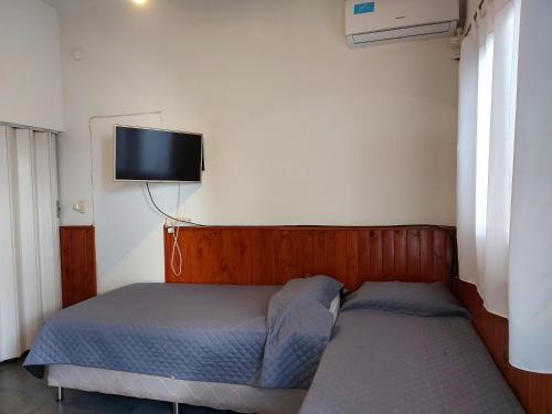 Departamento centro salta في سالتا: غرفة نوم بسريرين وتلفزيون على الحائط