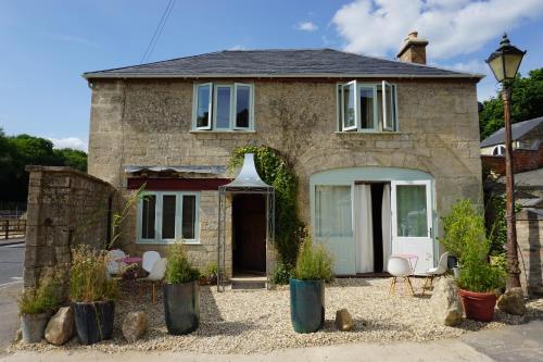 a stone house with a front door and a patio at The Coach House and The Stable in Woodchester