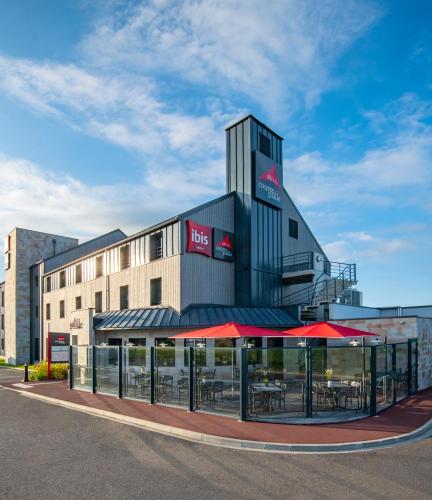 a building with tables and chairs in front of it at ibis Pontorson Baie Du Mont Saint Michel in Saint-Georges-de-Gréhaigne