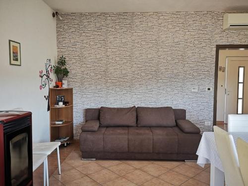 ein Wohnzimmer mit Sofa und Ziegelwand in der Unterkunft Apartma Čeh in Gabrovica pri Črnem Kalu