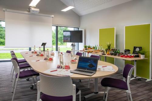 a conference room with a table with a laptop on it at ibis Pontorson Baie Du Mont Saint Michel in Saint-Georges-de-Gréhaigne