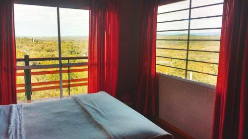 1 dormitorio con cortinas rojas y 1 cama frente a una ventana en Balcones de Molinari en Cosquín