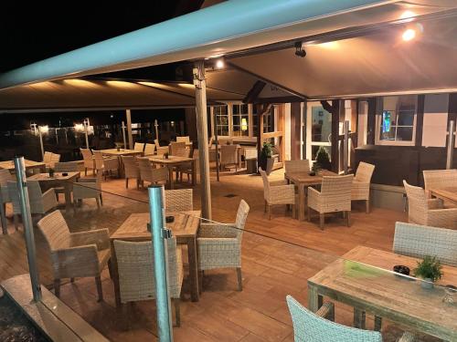 a restaurant with tables and chairs on a deck at Dötlinger Hof in Dötlingen