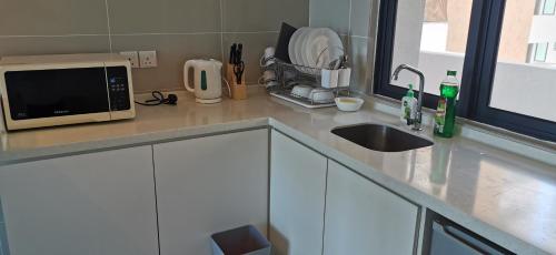 a kitchen counter with a microwave and a sink at Dwharf Seaview Executive Suit PortDickson in Port Dickson