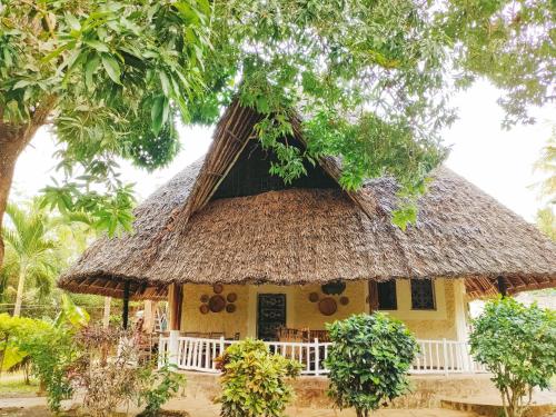 a small yellow house with a thatched roof at Upani in Diani in Diani Beach
