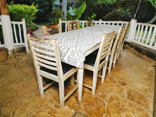 a table and chairs with a table and a fence at Upani in Diani in Diani Beach