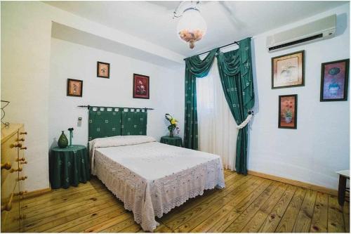 1 dormitorio con 1 cama con cortinas verdes y ventana en Cortijo Rural Español Ideal para desconectar, en Villanueva de Mesía