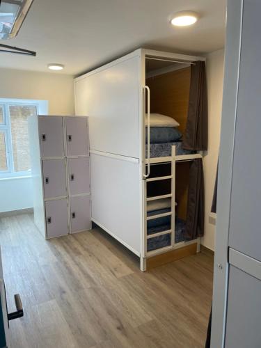 ロンドンにあるスマート カムデン イン ホステルの白い大型キャビネット、二段ベッドが備わる客室です。