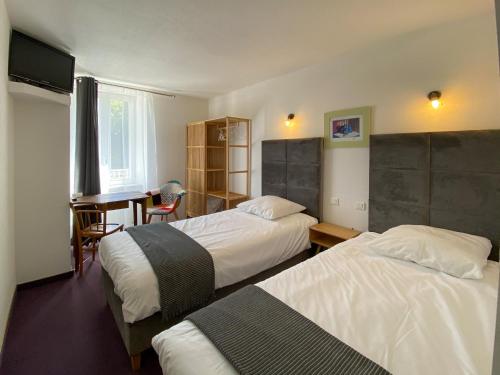 a hotel room with two beds and a desk at Hôtel Les Tilleuls de Pareloup à Salles-Curan in Salles-Curan