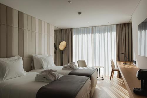 リスボンにあるLumen Hotel & The Lisbon Light Showのベッド2台と机があるホテルの部屋