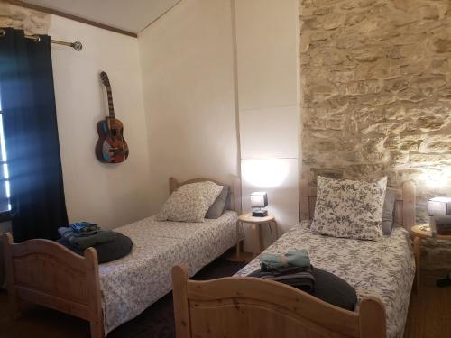 two beds in a room with a guitar on the wall at Appartement à FONTAINE DE VAUCLUSE in Fontaine-de-Vaucluse