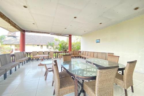 a dining room with tables and chairs on a patio at SUPER OYO Flagship 90644 Cottage Nalendra Nuansa Nusantara in Subang