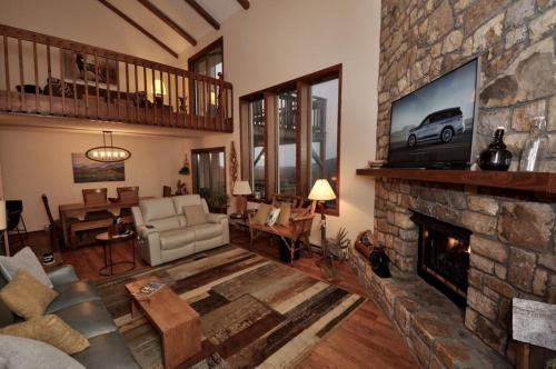 a living room with a stone fireplace with a tv at The Crest 200C condo in Sugar Mountain