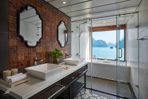 La salle de bains est pourvue de 2 lavabos et d'une douche en verre. dans l'établissement Halong Capella Cruise, à Hạ Long