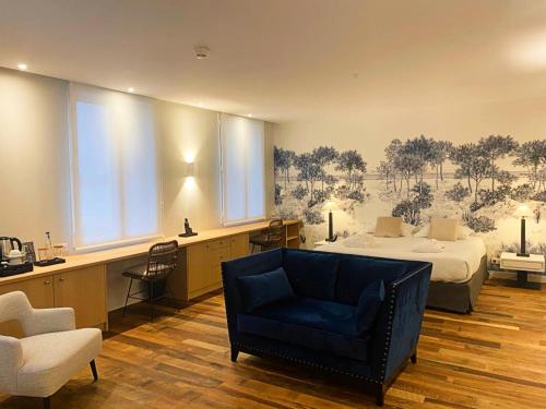 a bedroom with a bed and a blue chair at Hôtel de la Plage - Saint Jean de Luz in Saint-Jean-de-Luz
